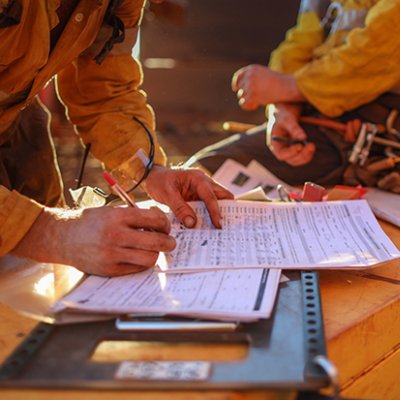 Close up of mine worker in high vis writing on a piece of paper